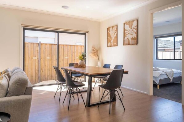 A modern interior with a dining table, chairs, a sofa, and a bed.