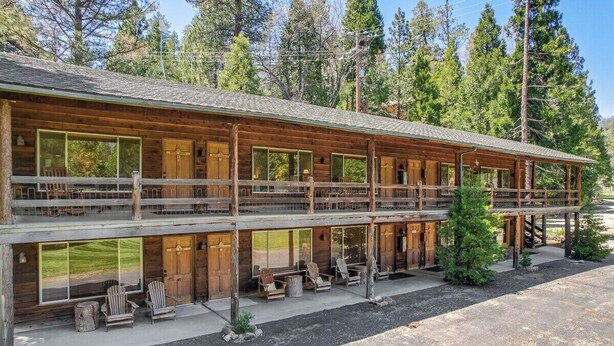 A two-story log cabin with a balcony, large windows, and outdoor seating. - Bear's Den Camp Nelson Lodge #5 (Springville)