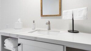 A bathroom with a white sink, a mirror, a towel rack, and a towel dispenser. - Bear's Den Camp Nelson Lodge #5 (Springville)