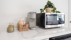 A kitchen counter with a microwave, a coffee maker, a ceramic pitcher, and a basket with items. - Timberline Retreat Camp Nelson Lodge #3 (Springville)