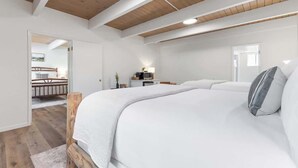A bedroom with a large bed, wooden ceiling beams, a bedside table with a lamp, and a view of a balcony. - Camp Nelson Lodge | Room 4 | Sierra Nevada Retreat (Springville)