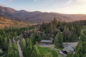 Luchtfoto van een lodge, omringd door dicht bos en bergen.