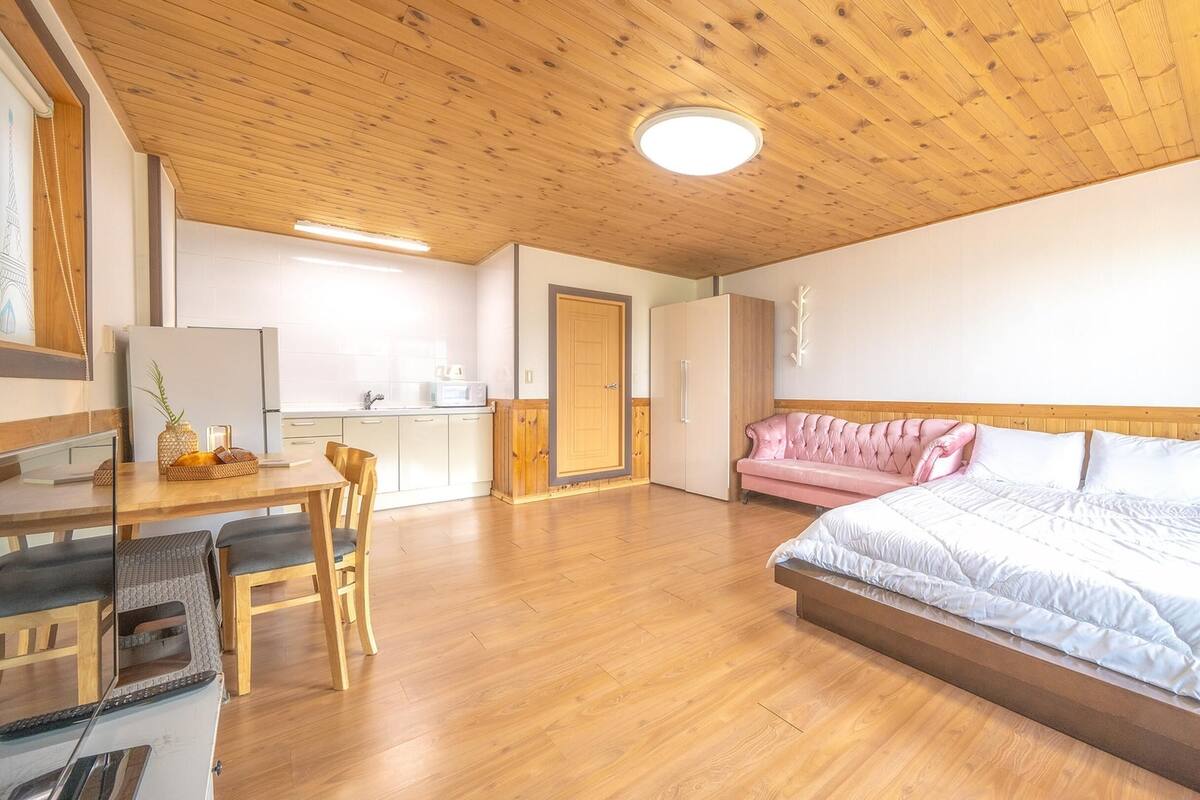 Ein geräumiges Schlafzimmer mit einem großen Bett, einer Holzbalkendecke und einer Küchenzeile im Hintergrund.