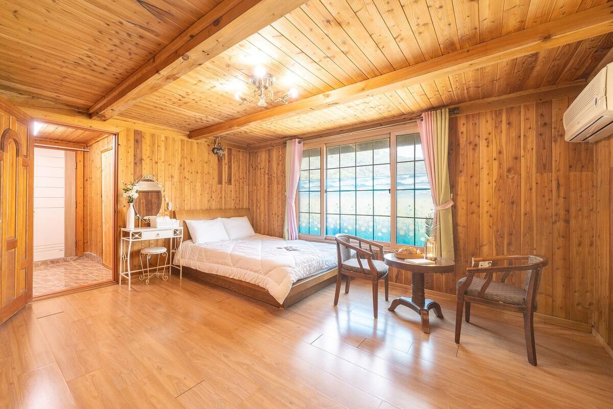 Ein Zimmer in einer Holzhütte mit einem Bett, einem Schreibtisch und einem Fenster.