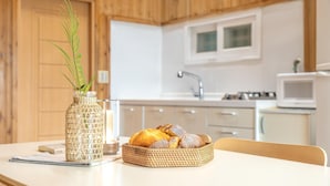 A kitchen with white cabinets, a microwave, and a wicker basket with bread on a table. - Gapyeong Gold Castle Pension (Gapyeong)