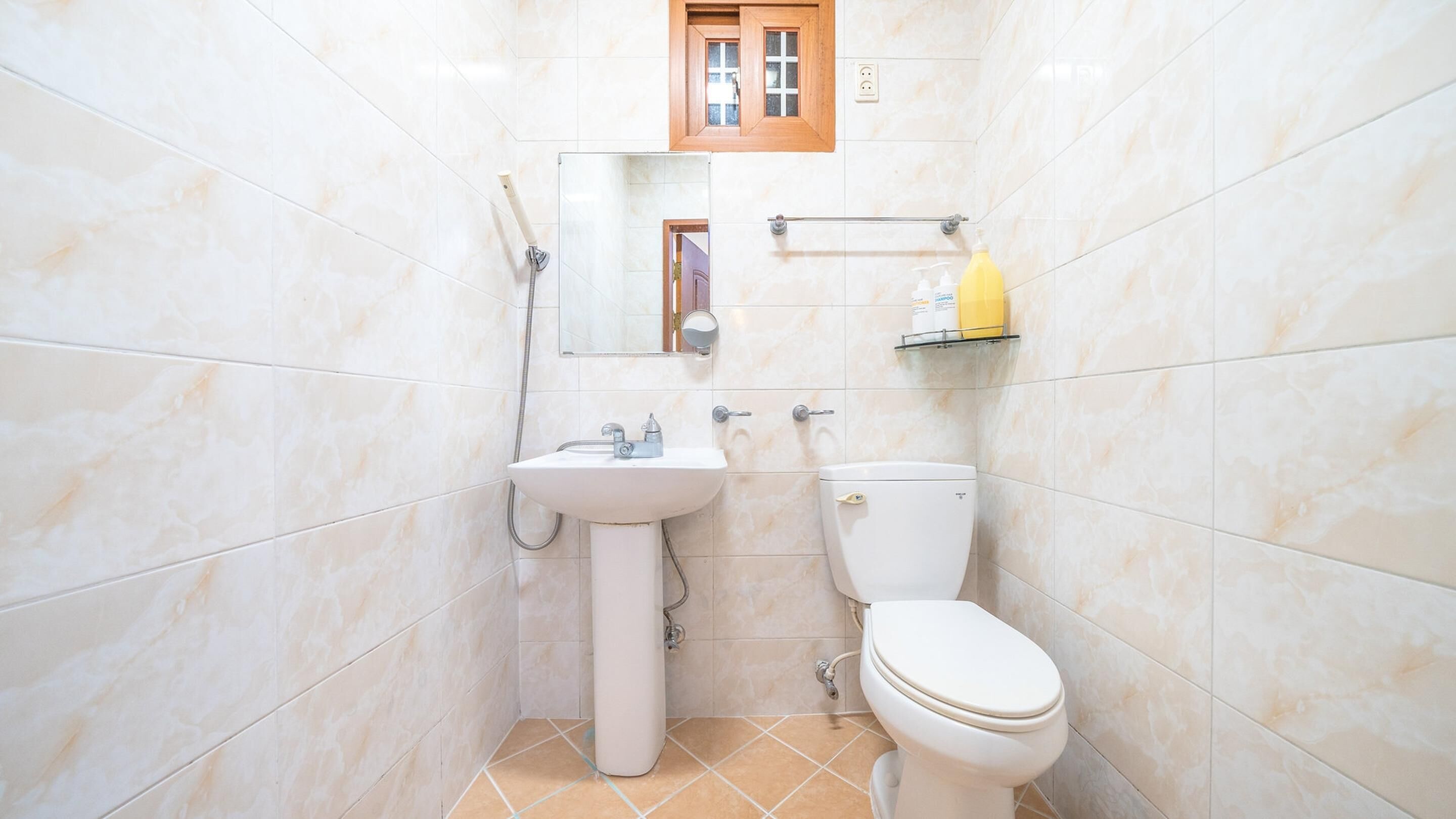 Un baño con lavamanos, inodoro y espejo.