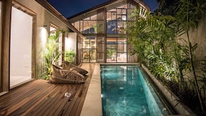 A modern house with a swimming pool, wooden deck, and large windows. - Villa Nina (Canggu)