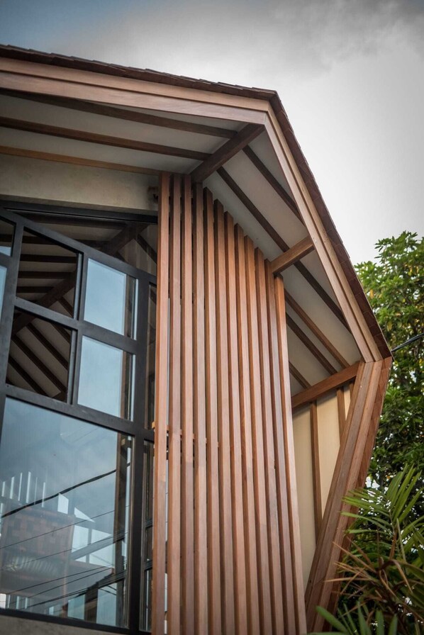 A corner of a building with a sloped roof and a window with a grid pattern.