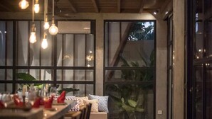 A modern interior with a bar area, seating, and a view of the outdoors. - Villa Nina (Canggu)