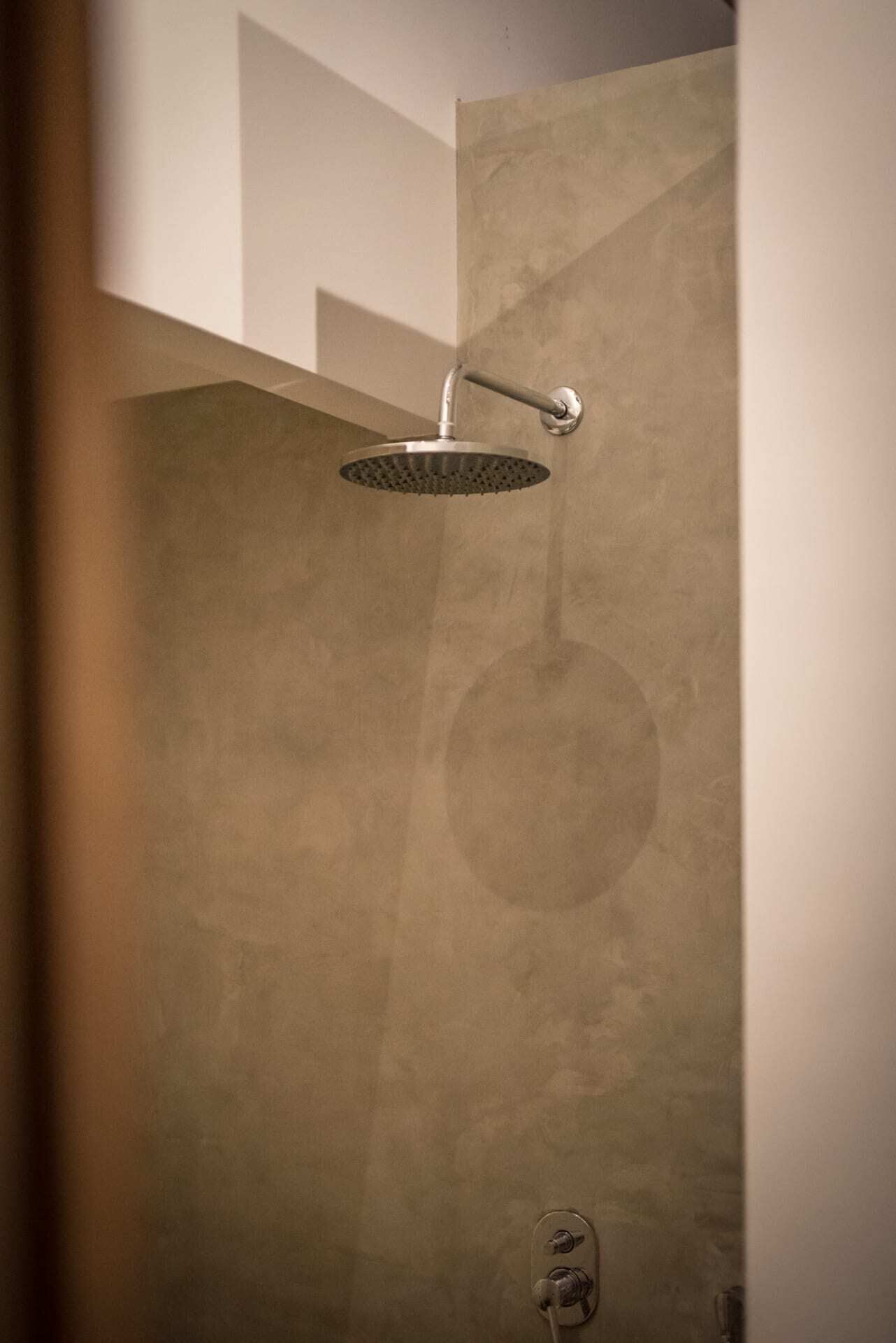 Een moderne douche met een gebogen douchekop, bevestigd aan een geribbelde wand.