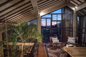 Relax in this serene space with a large window offering a view of the outdoors, a wooden bench, and two cushioned chairs.