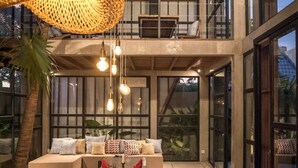 A spacious dining area with a long table set for a meal, a high ceiling, and large windows providing natural light. - Villa Nina (Canggu)