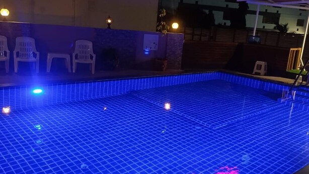 Une piscine aux carreaux bleus, avec quelques chaises disposées le long du bord.