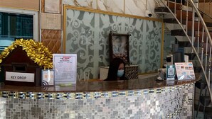 Un espace d’accueil d’hôtel avec un comptoir recouvert de mosaïques, un endroit pour déposer les clés et un escalier doté d’une rampe en verre.