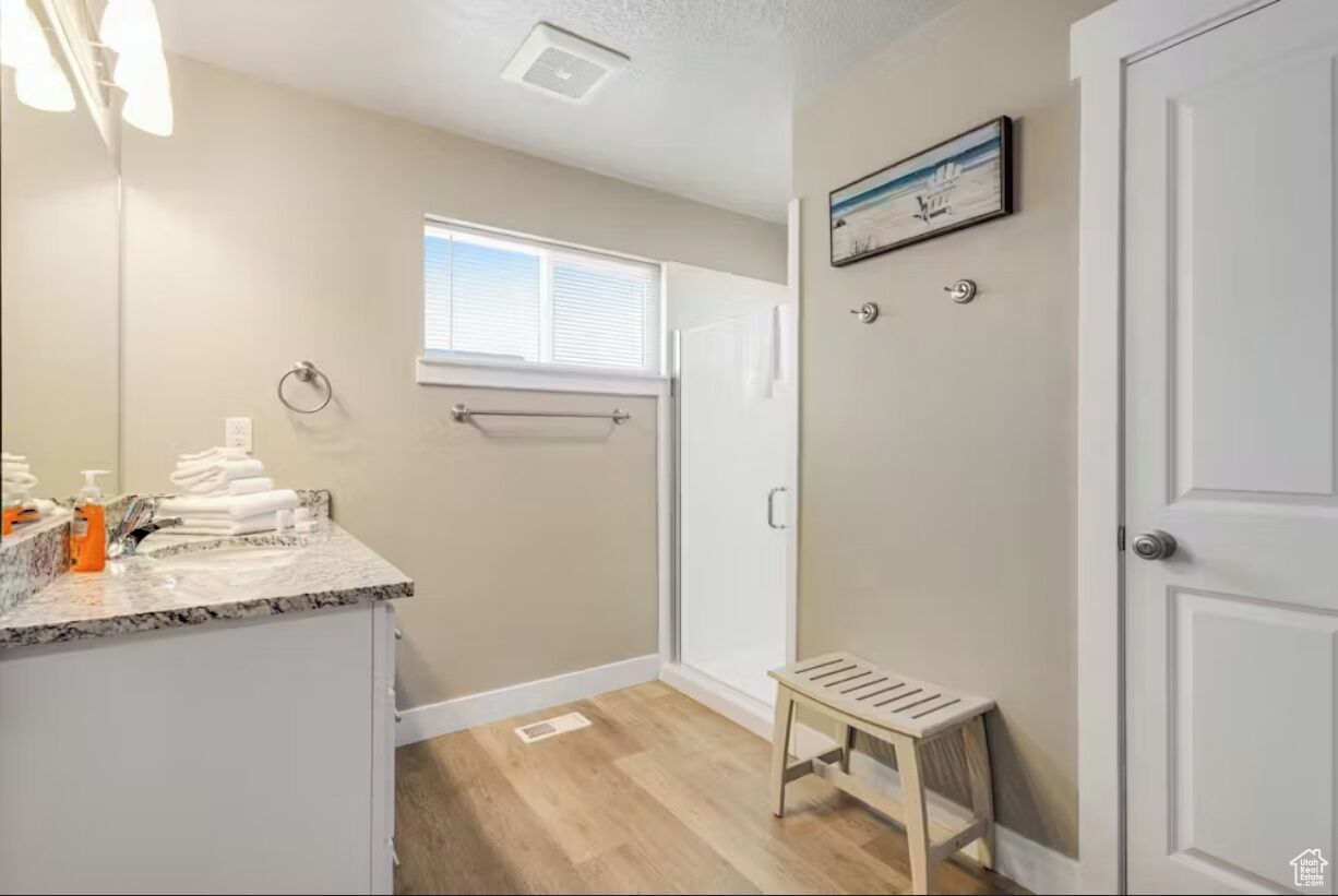 A bathroom with a shower, a small window, a towel rack, and a bench.