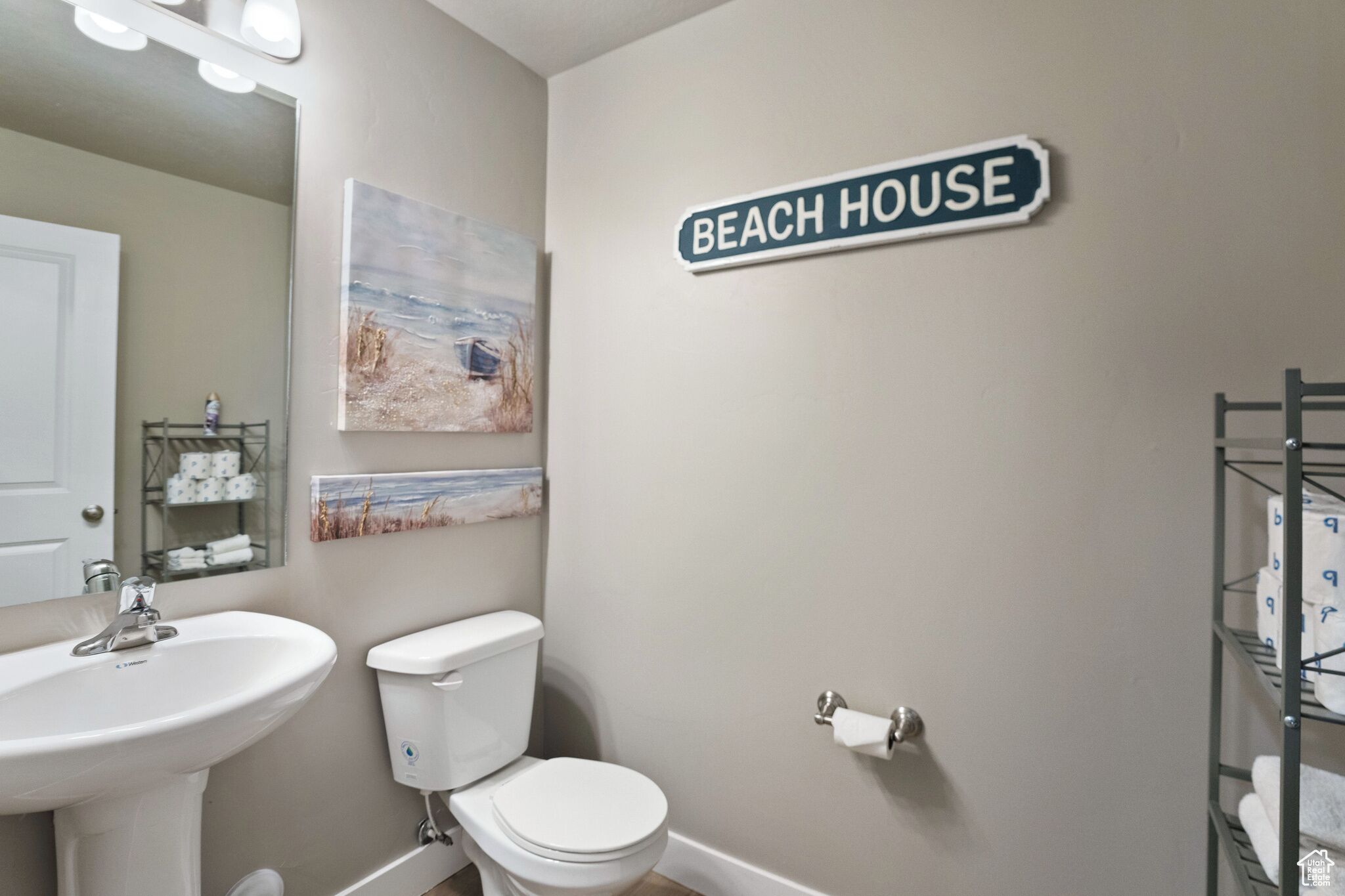 Une salle de bain avec un lavabo, des toilettes et un panneau indiquant « Beach House » sur le mur.
