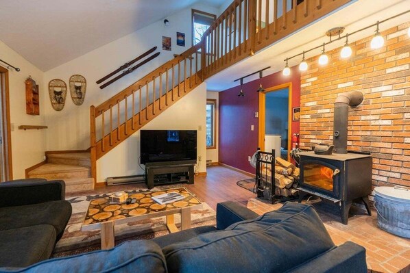 A living room with a fireplace, a staircase, and a TV.