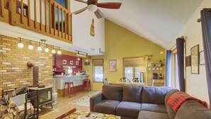 A living room with a sofa, a coffee table, a fireplace, and a kitchen in the background. - Cozy Private Single Family Home, Campton NH-MV118C (Campton)