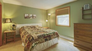A bedroom with a bed, a dresser, a nightstand with a lamp, a floor lamp, and a window with blinds. - Cozy Private Single Family Home, Campton NH-MV118C (Campton)