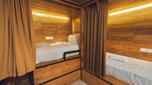 A compact room with wooden walls and a single bed with white bedding. - dBeds Kuta Beach (Kuta)