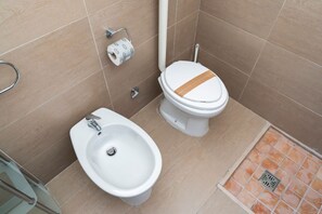 Une salle de bain équipée d’un bidet, de toilettes et d’un petit lavabo.