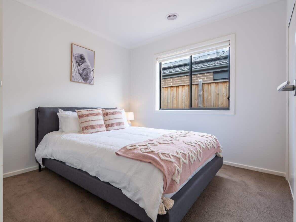 A bedroom with a bed, a window, and a picture on the wall.