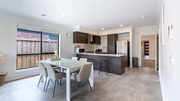A modern kitchen with a dining area, a large window, and a view of the backyard.