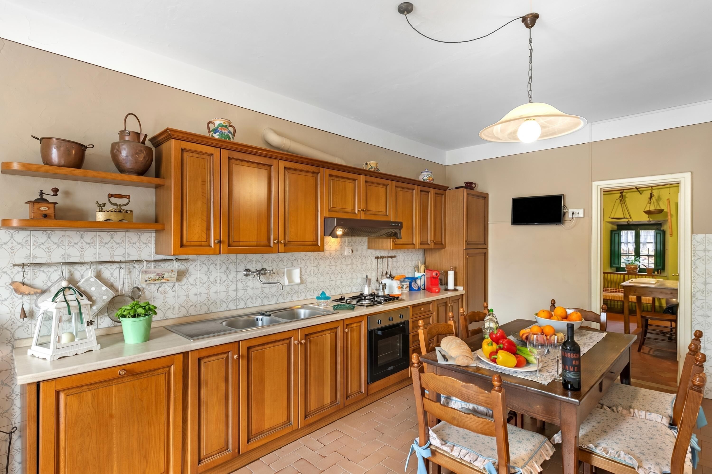 A kitchen with wooden cabinets, a stove, a sink, and a dining area with a table and chairs.