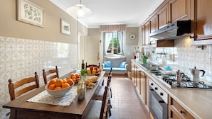 A kitchen with wooden cabinets, a stove, and a dining area with a table set for a meal. - Villa Ortensie Garden with Amazing View (Marliana)