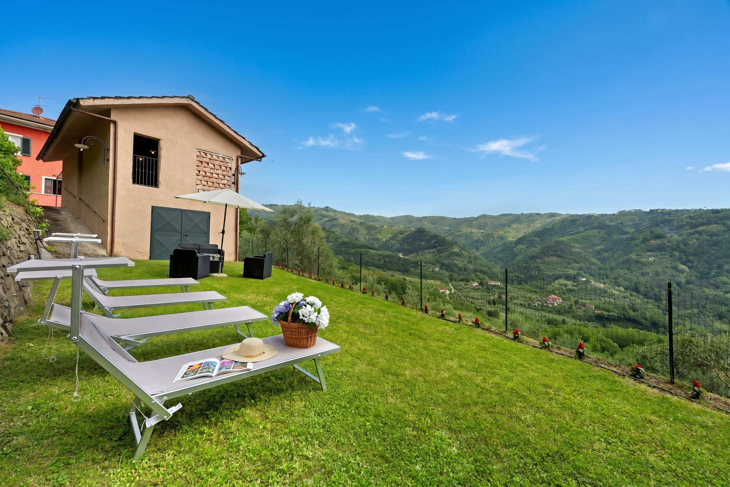 A building with a sloped roof, a balcony, and a view of a green valley.
