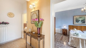 A hotel room with a bed, bedside table, nightstand, and a painting on the wall. - Villa Ortensie Garden with Amazing View (Marliana)