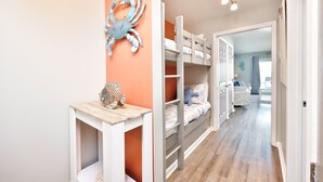 Ein Kinderzimmer mit Etagenbett, einem Holztisch und einer Wanddekoration mit einem Krebs.