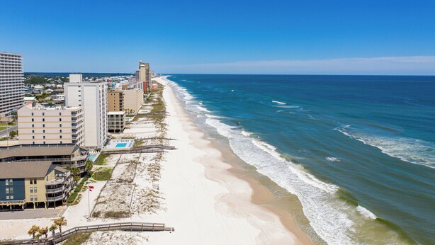 Ein Küstenhotel mit mehreren Gebäuden, einem Strand und Meerblick.