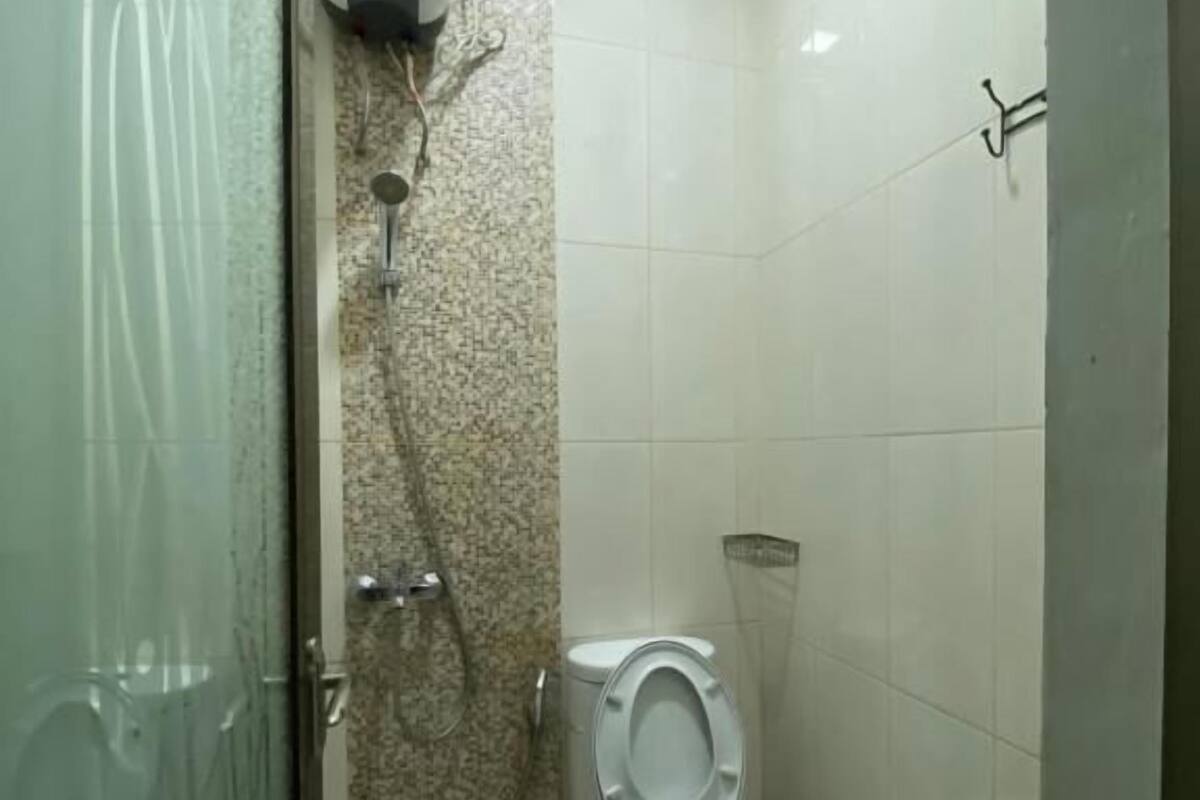 A small, tiled bathroom with a toilet, a shower, and a hand dryer.