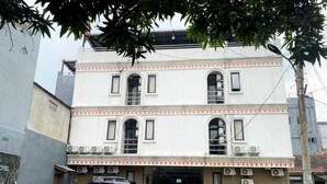 A two-story building with a white facade, multiple windows, and an air conditioning unit on the ground floor. - ANUGRAH INN HOTEL (Ciakar)