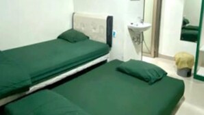 A room with two single beds, a small bedside table, a mirror, and a sink. - ANUGRAH INN HOTEL (Ciakar)