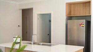 A modern kitchen with a stainless steel refrigerator, a white countertop, and a wooden cabinet above the sink. - Homely Entire house in Clyde (Clyde)