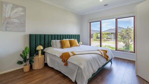 A bedroom with a large bed, a view of the outside, and a potted plant. - Homely Entire house in Clyde (Clyde)