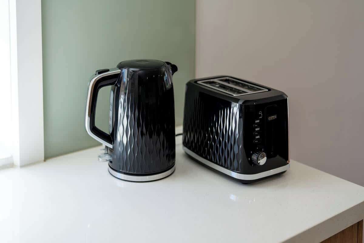 A black kettle and toaster on a white countertop.