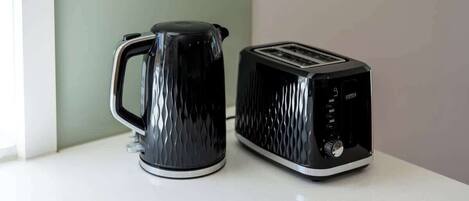 A black kettle and toaster on a white countertop.