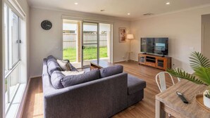 A living room with a sofa, TV, and dining table. - Homely Entire house in Clyde (Clyde)