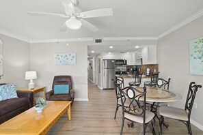 A modern living room with a sofa, coffee table, and a dining area with chairs and a table. - South Beach Condo Hotel (Treasure Island)