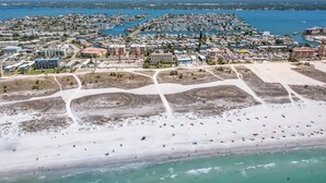 An aerial view of a coastal town with a sandy beach, marina, and residential buildings. - South Beach Condo Hotel (Treasure Island)