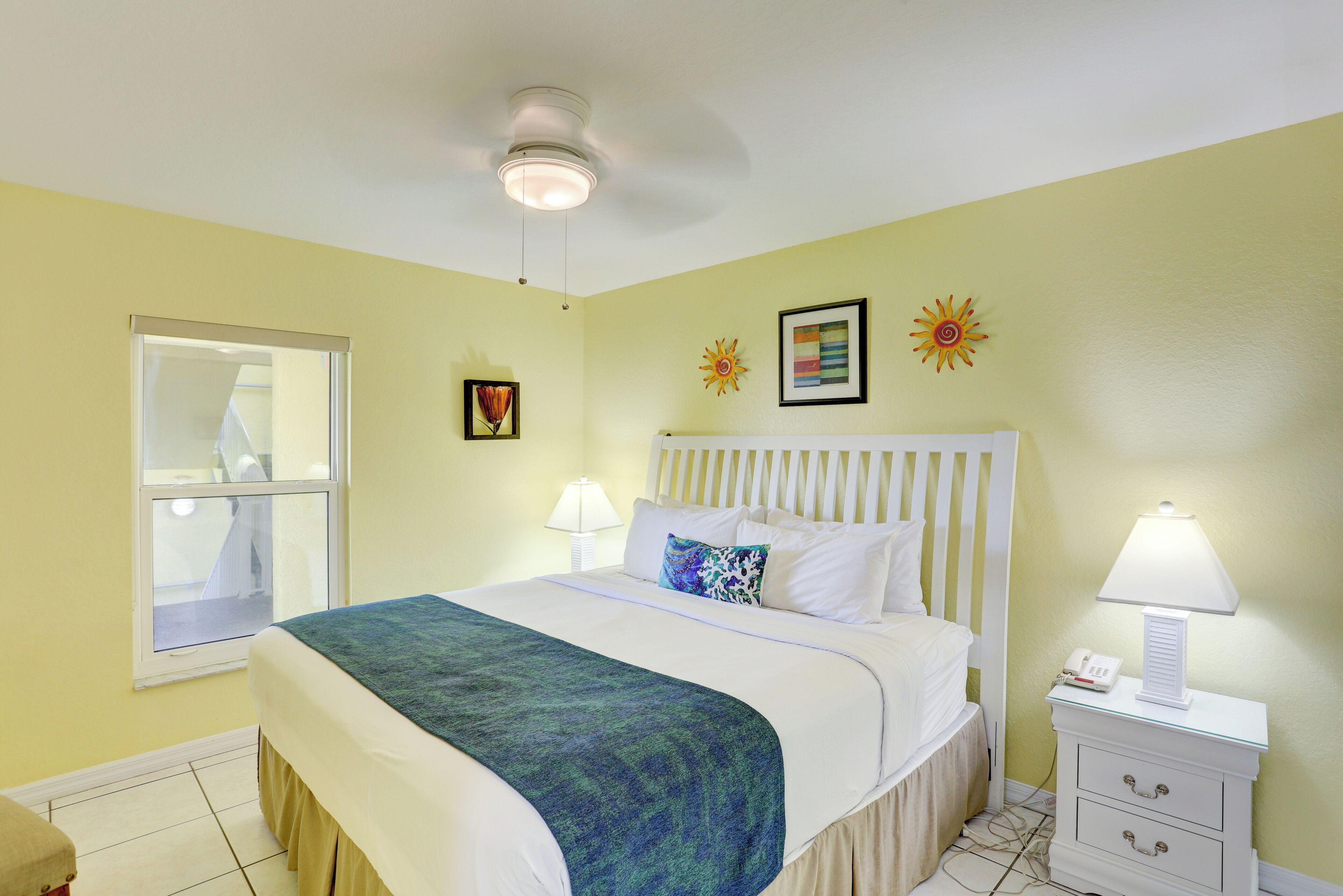 A bedroom with a bed, bedside lamps, a window, and a nightstand.