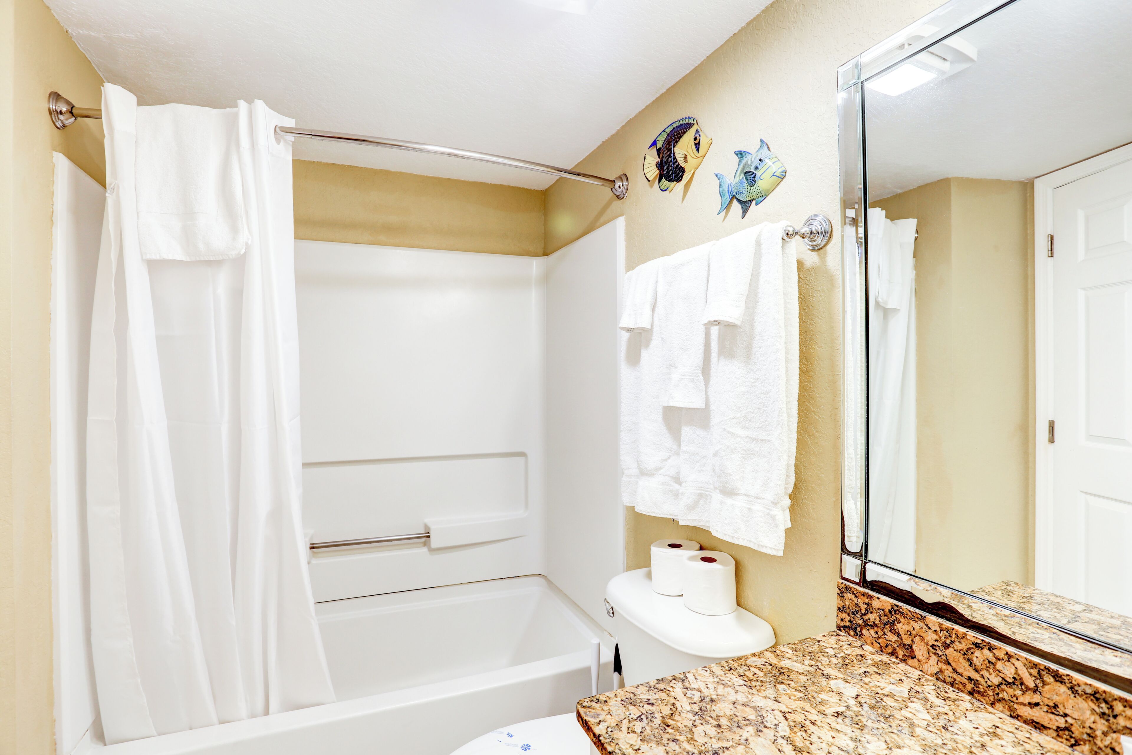 A bathroom with a bathtub, a toilet, a sink, and a mirror.