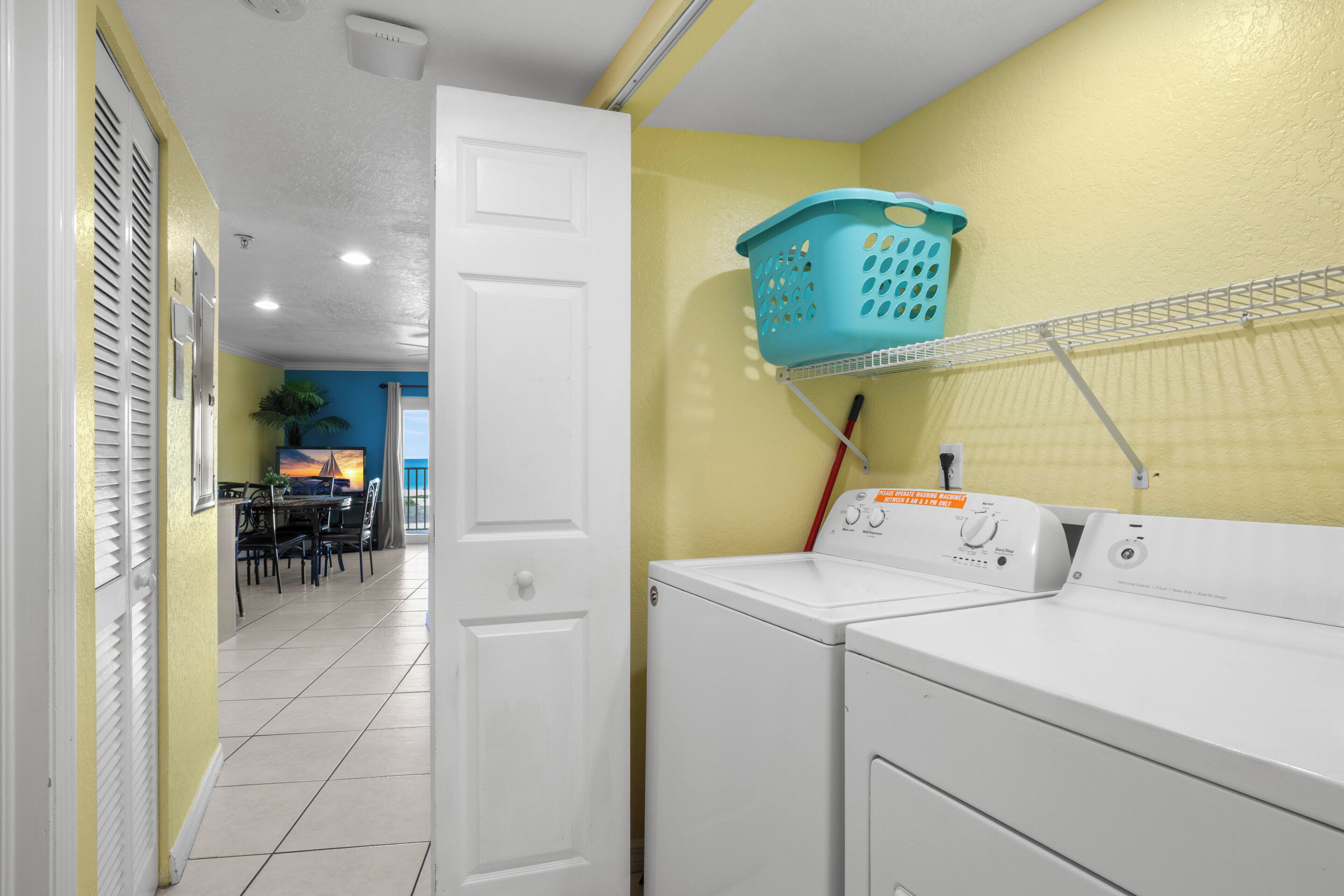 A laundry area with a washing machine, a drying rack, and a basket.