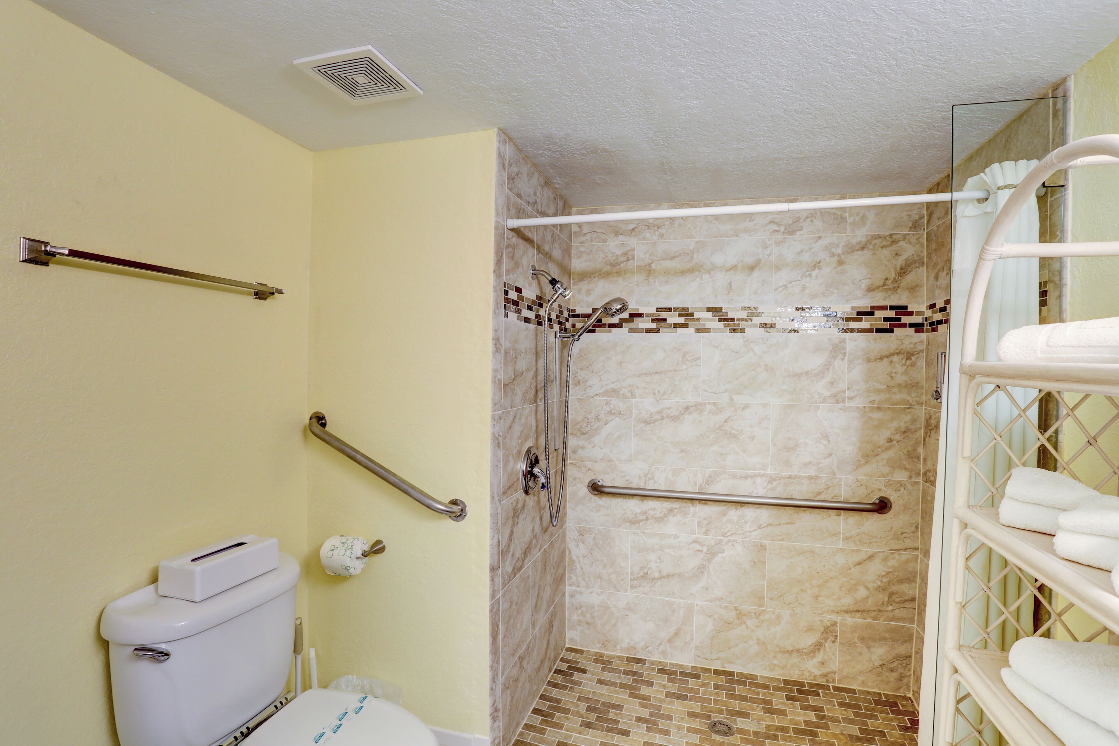 A bathroom with a toilet, a shower with a glass door, and a towel rack.