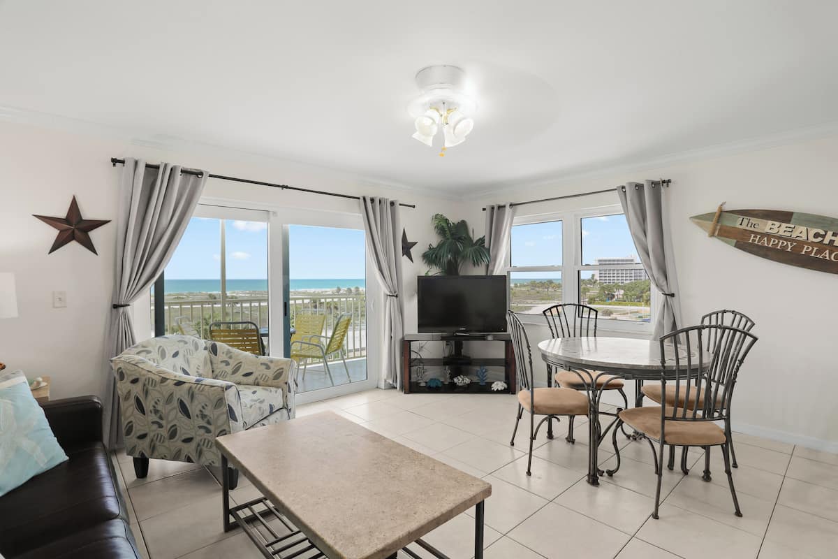 A living room with a TV, dining table, chairs, a sofa, and a star decoration.