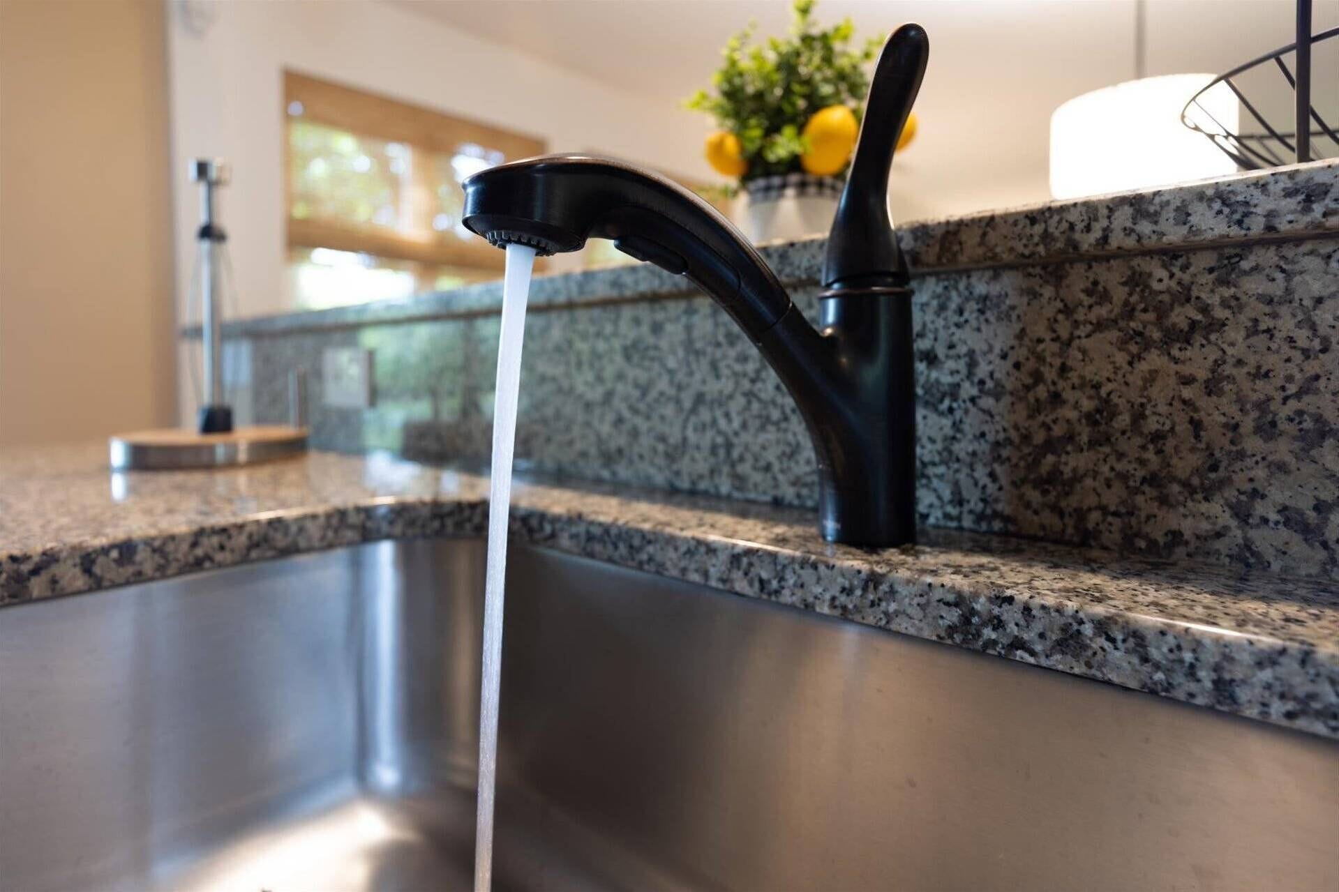 Una cocina con encimera de granito, grifo negro y pileta de acero inoxidable.