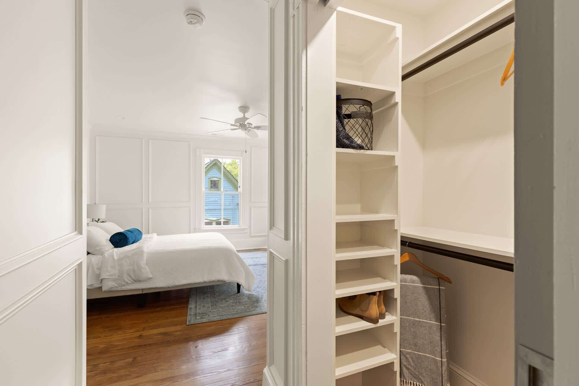 A bedroom with a bed, a window, a closet with shelves, and a ceiling fan.